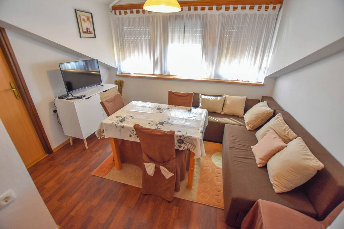Un salon chaleureux avec une table à manger, un canapé et un téléviseur posé sur un meuble.