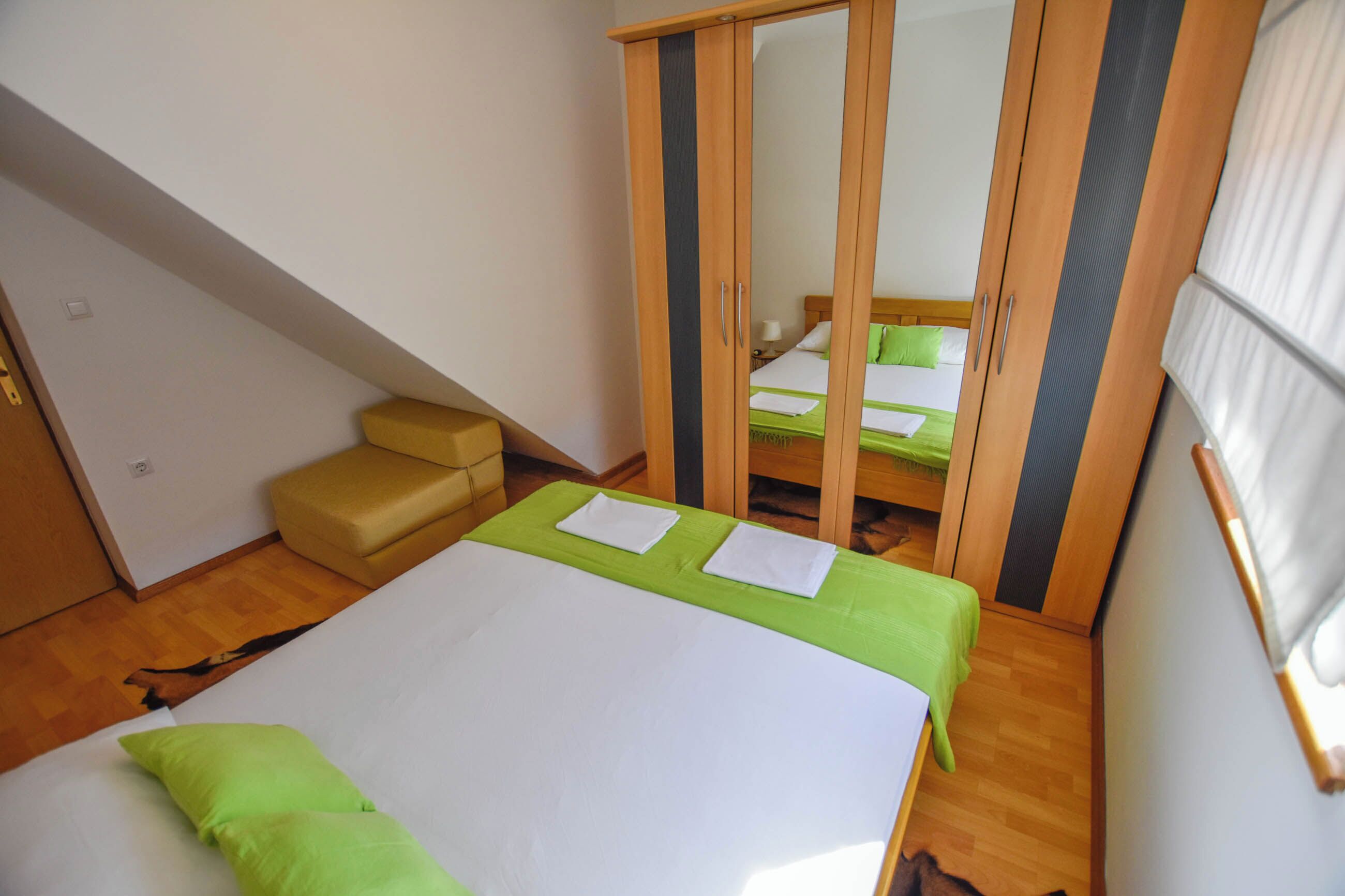 Une chambre à coucher comprenant un lit, une armoire, un miroir et un petit coin salon.