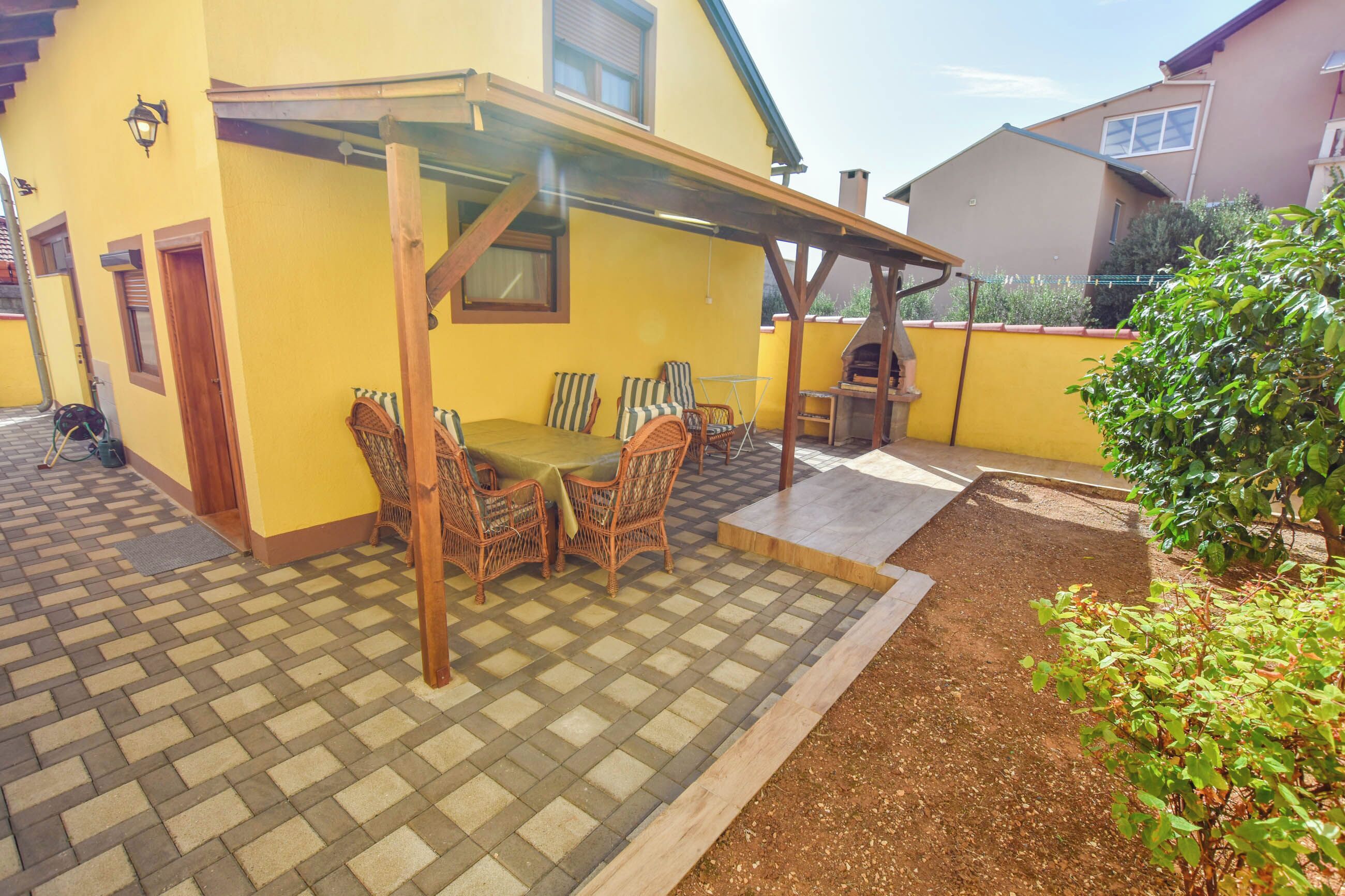 A patio with a table and chairs, a pergola, and a brick floor.
