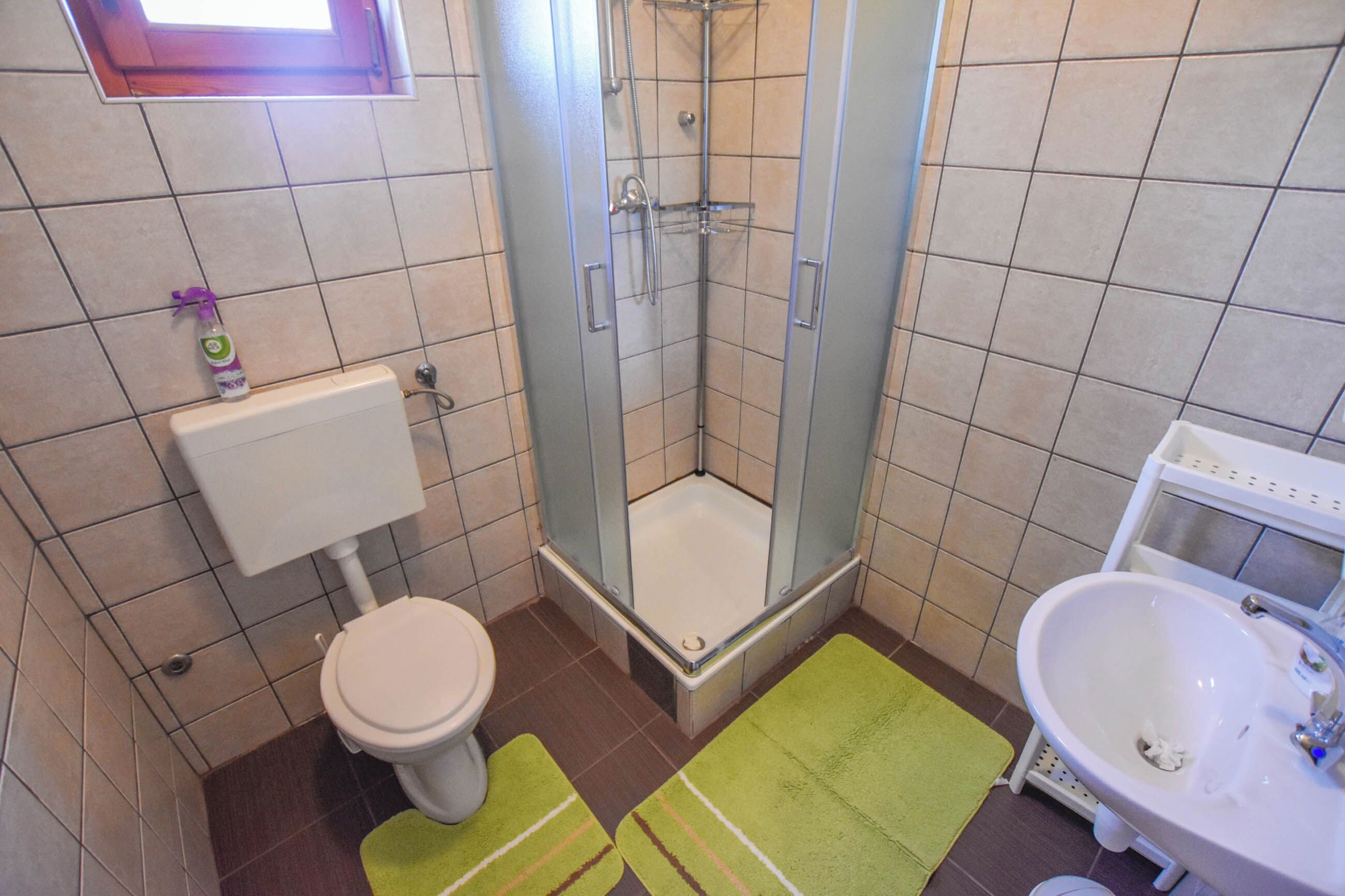 A bathroom with a toilet, a shower, and a sink.