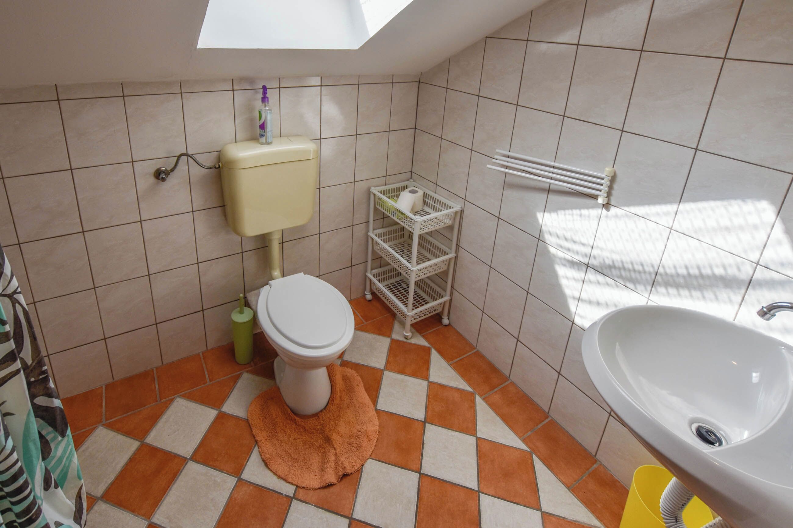 Ein Badezimmer mit Toilette, Waschbecken und Fliesenboden.