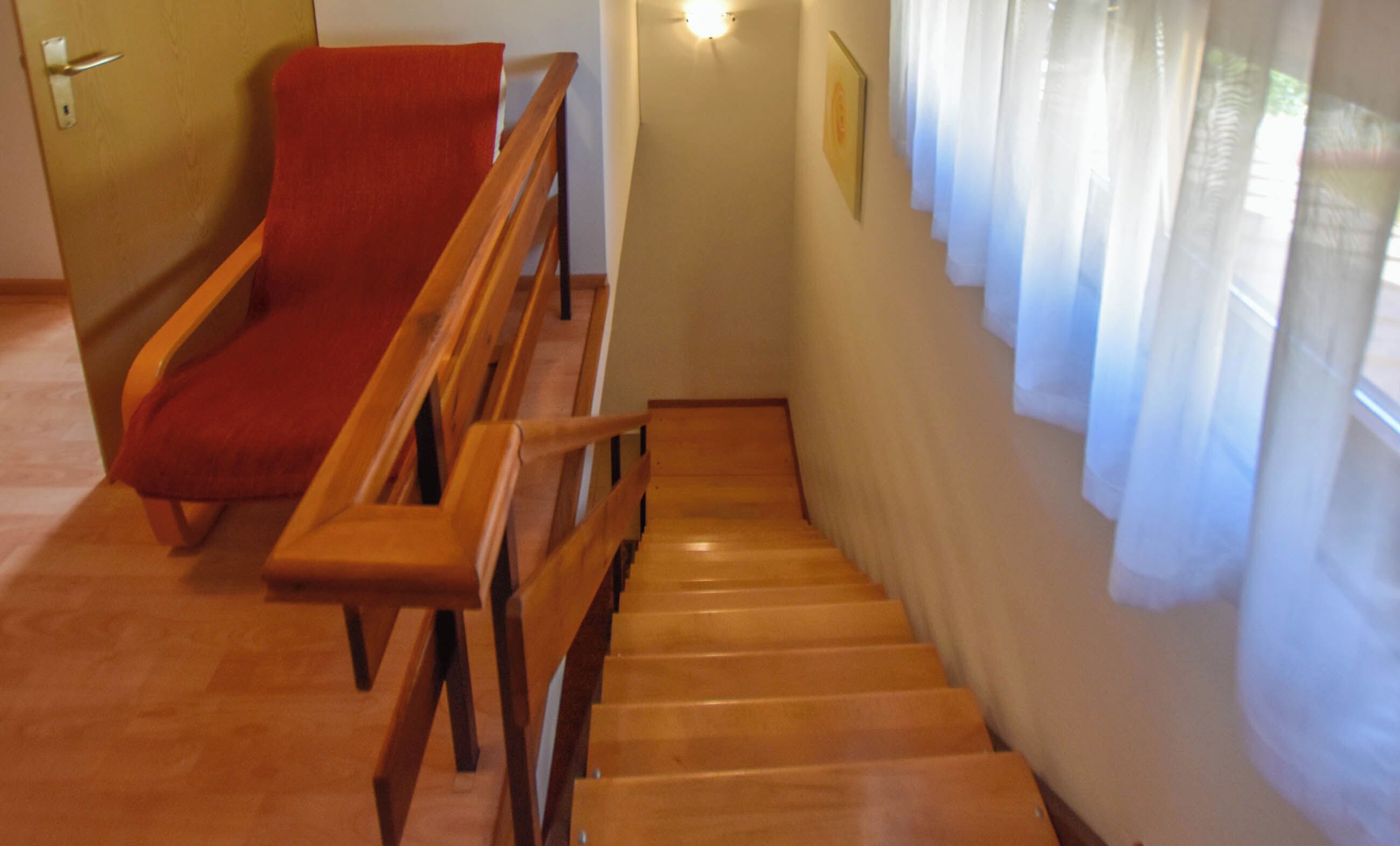 Eine Holztreppe mit einem roten Stuhl oben.