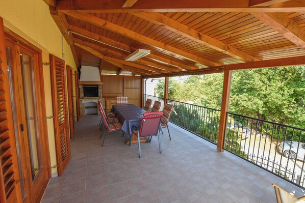 Un espacio de comedor al aire libre cubierto con una mesa y sillas, una zona de cocina y vistas a la vegetación circundante.
