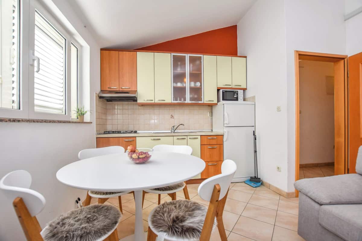 Une cuisine compacte avec un coin repas, comprenant une table blanche, des chaises et un four à micro-ondes.