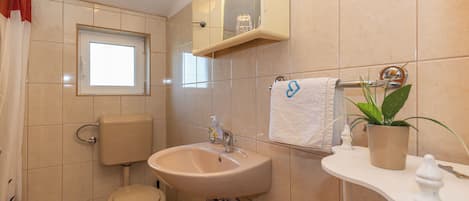 Un baño con inodoro, lavamanos y espejo.
