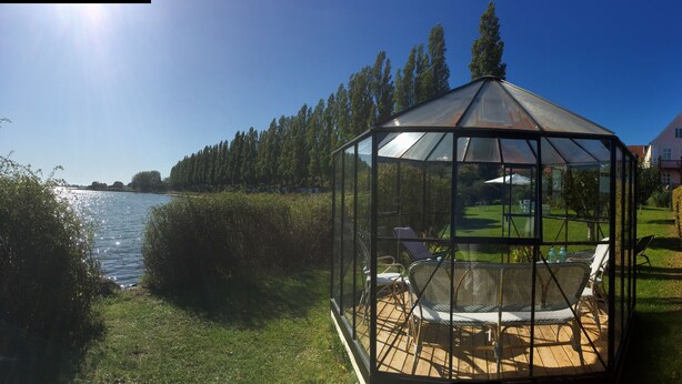 A glass gazebo with a view of a lake and a flag.
