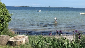 A calm lake with a small boat and a person standing in the water.