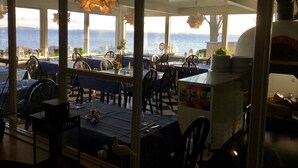 An outdoor dining area with tables and chairs, overlooking a body of water.