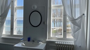 A bathroom with a sink, mirror, and windows overlooking a body of water.