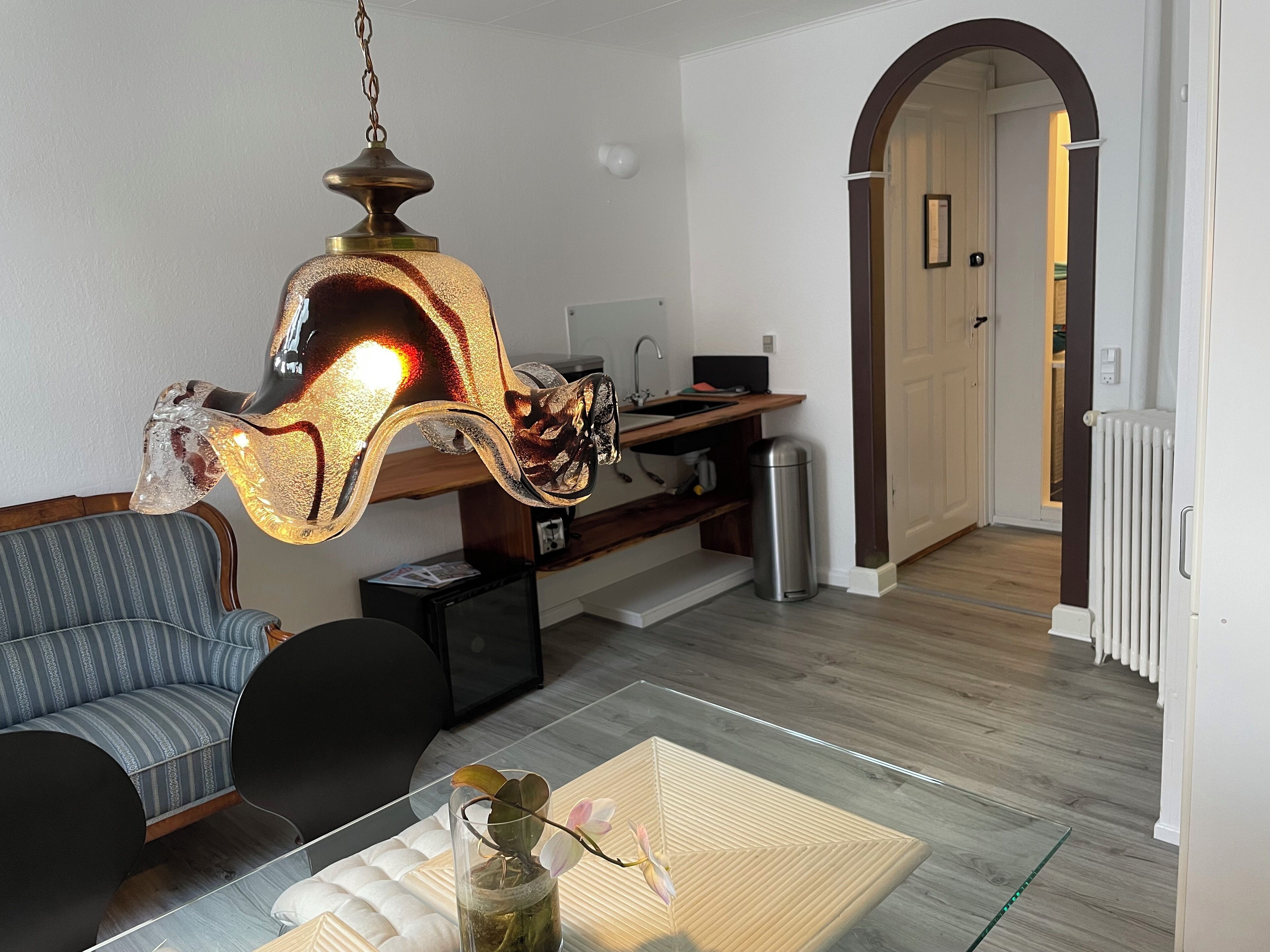 A modern living room with a glass coffee table, a sofa, and a unique hanging light fixture.