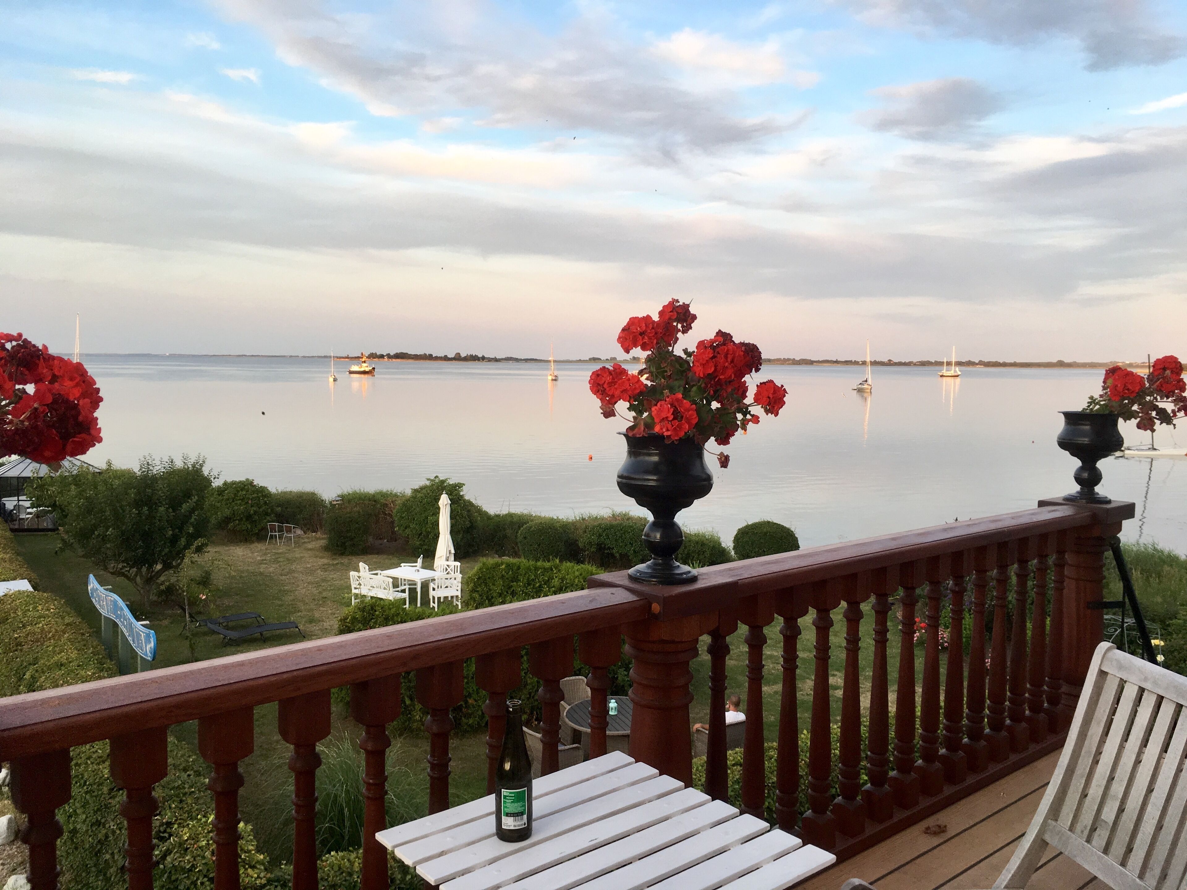 Un balcón con vistas a un lago tranquilo, barcos y una baranda de madera.