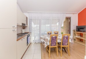 A modern kitchen with a dining area, featuring a kitchen island, wooden chairs, and a dining table with a patterned tablecloth. - Apartments Mira I (Vodice)