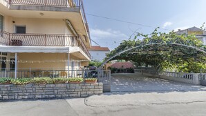 A multi-story building with a balcony, potted plants, and a gated entrance. - Apartments Mira I (Vodice)