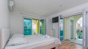 Quarto moderno com uma cama grande, guarda-roupa e porta de vidro deslizante para uma varanda.