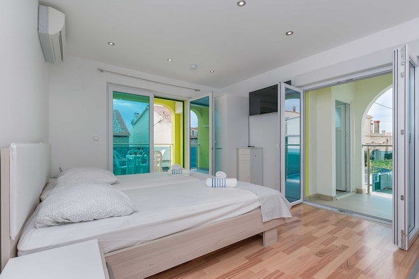 A modern bedroom with a large bed, a wardrobe, and a sliding glass door leading to a balcony.