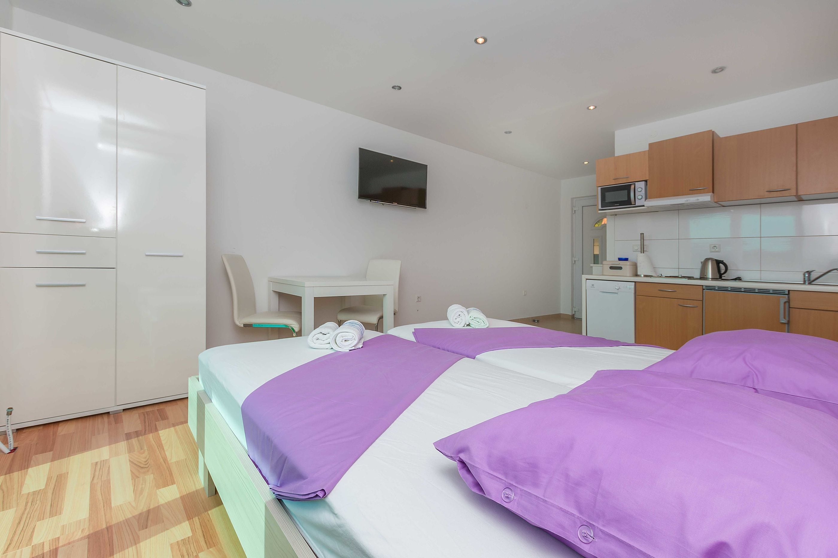 Une chambre d’hôtel avec deux lits, un bureau, une chaise, une télévision et une kitchenette.