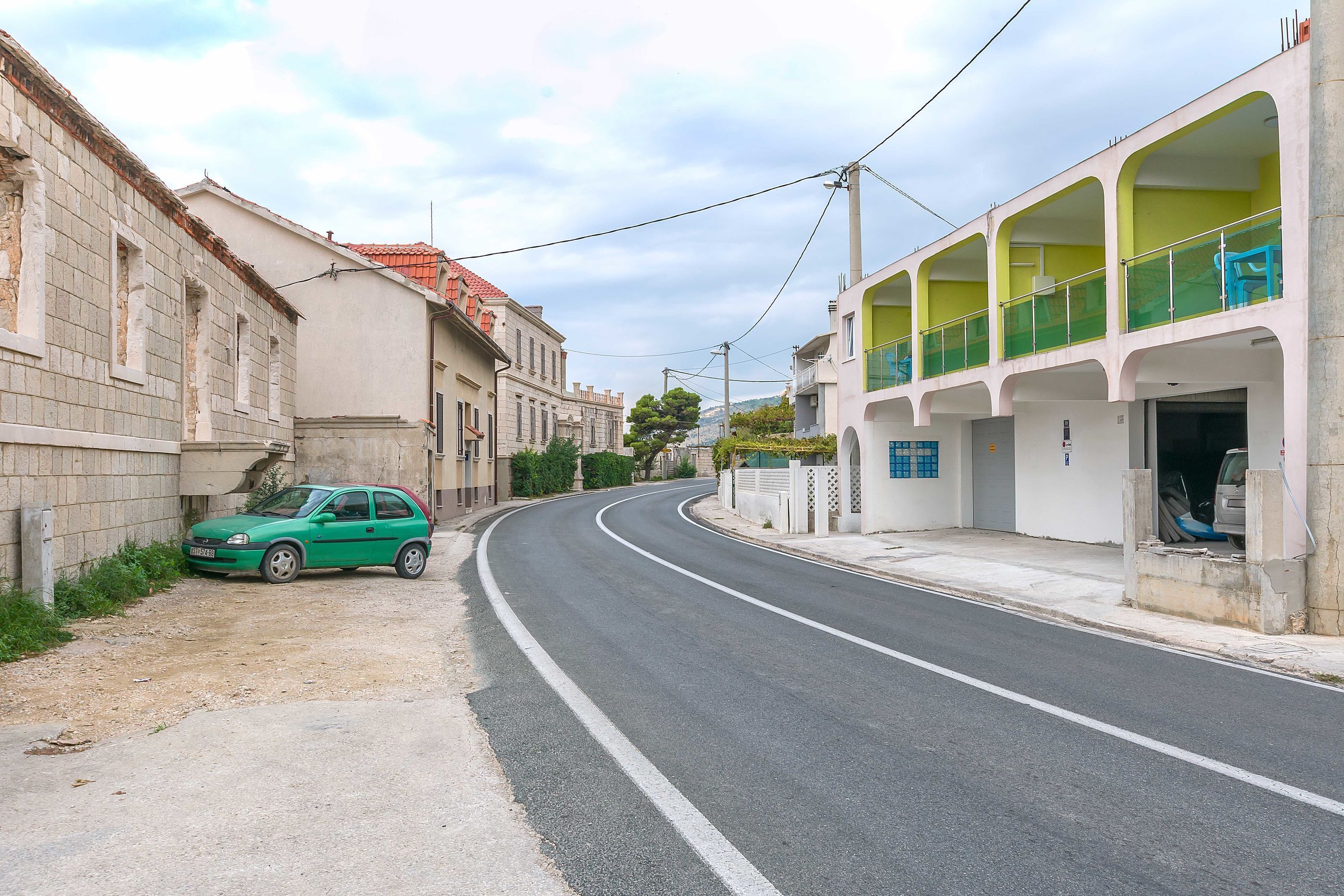 Une rue étroite où est garée une voiture verte sur le bord.