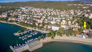 Vue aérienne d’une ville côtière avec un port de plaisance, des immeubles résidentiels et une plage.