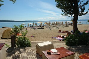 A beach with tents, lounge chairs, and umbrellas. - Apartment Roni (Crikvenica)