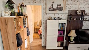 Ein Flur mit einem Holzregal, einem weißen Schrank, einer Couch und einer Wandlampe.