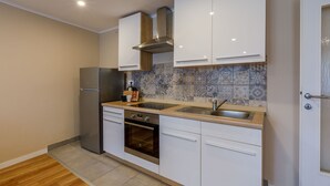 A modern kitchen with white cabinets, a stainless steel refrigerator, an oven, and a sink.