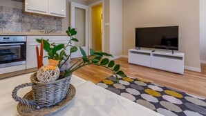 A modern kitchen with white cabinets, a built-in oven, and a decorative plant on the counter.