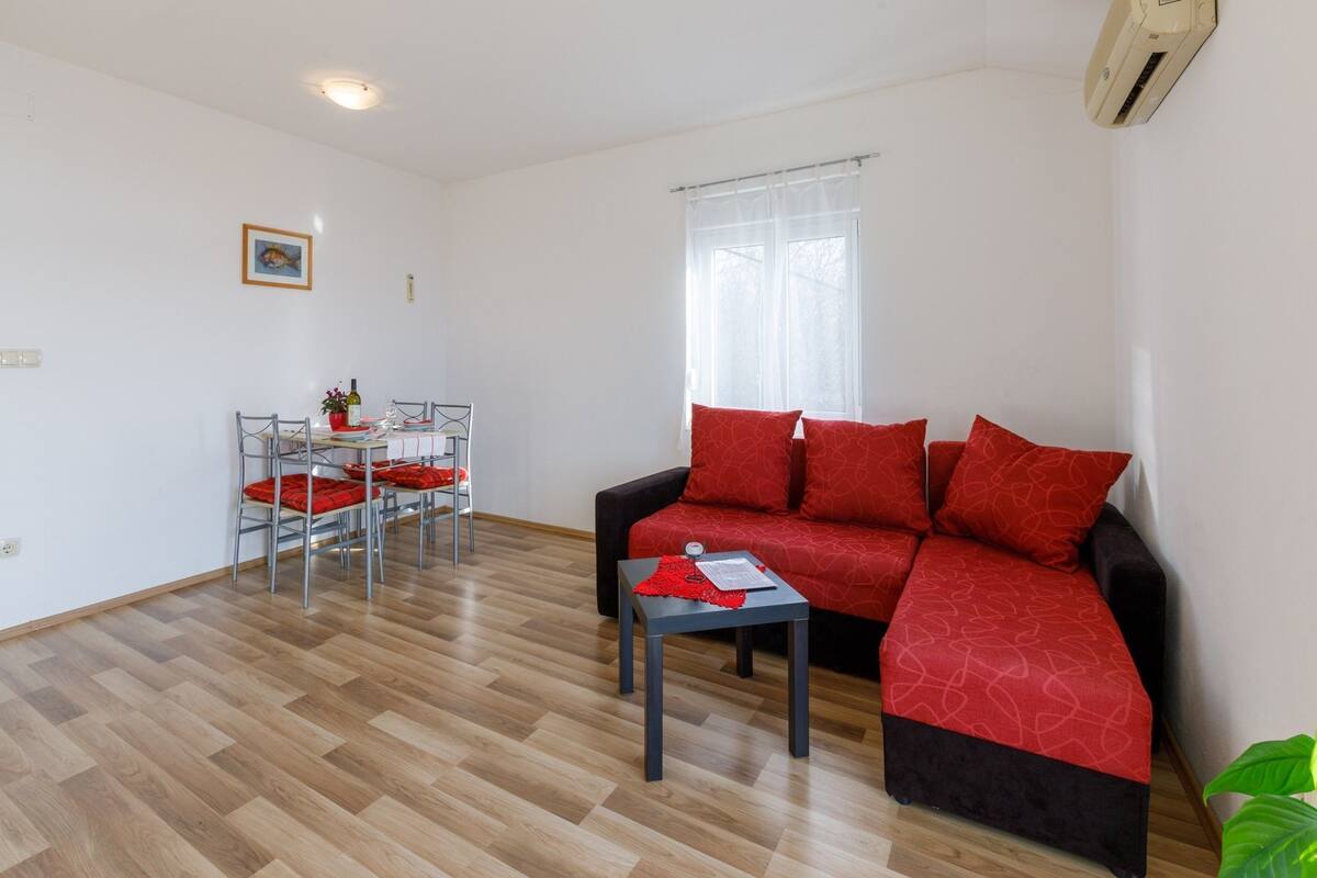 A compact living space with a sofa, a dining table with chairs, and a window with curtains.