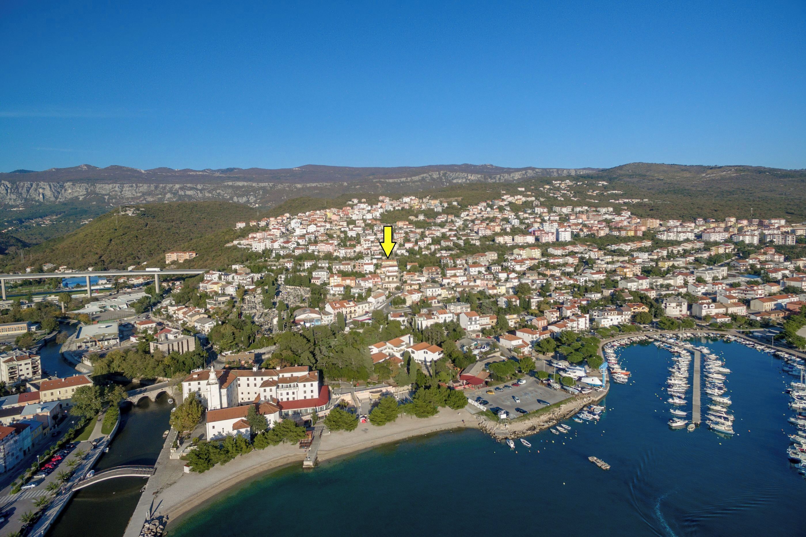 Vista aérea de un pueblo costero con un puerto deportivo, un puente y un río.