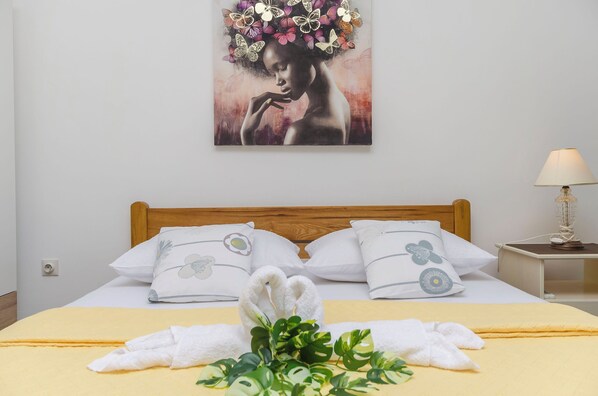 A neatly made bed with white pillows, a yellow bedspread, and a towel on the bed. - Apartment Robyn on the Beach (Srima)