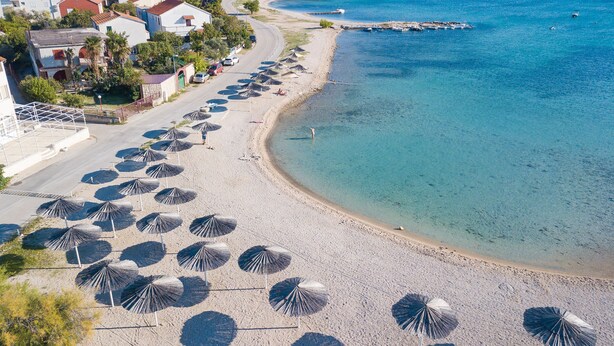 Una playa con hileras de sombrillas y una vista despejada del mar.