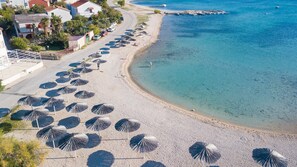Ein Strand mit mehreren Reihen von Sonnenschirmen und freiem Blick auf das Meer.