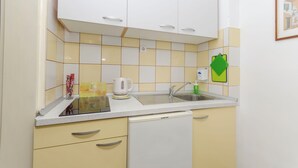 Una cocina con armarios blancos, una encimera blanca y un lavavajillas Koncar.