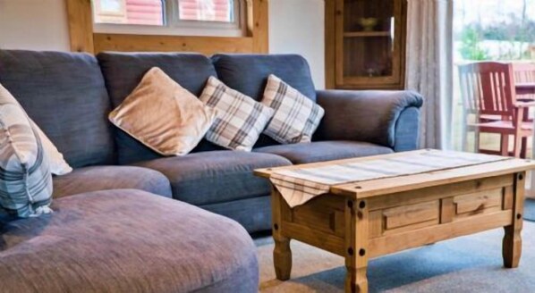 Een woonkamer met een modulaire bank, een houten salontafel en uitzicht op de natuur.