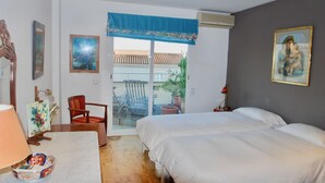 Un dormitorio con dos camas, un escritorio, una silla y un balcón con vistas.