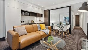 Un salon moderne avec un canapé en cuir, une table basse en verre et un coin repas comprenant une table et des chaises en verre.