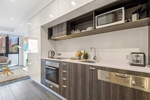 Una cucina moderna con elettrodomestici integrati, un'area pranzo con tavolo in vetro e vista sull'esterno.