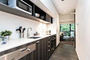 A modern kitchen with dark wood cabinets, stainless steel appliances, and a white countertop.