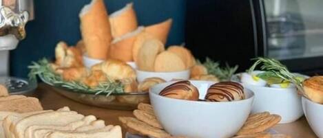 Una mesa de buffet con panes, pasteles y un procesador de alimentos.