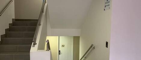 A staircase with handrails, a trash bin, and a door labeled "202".