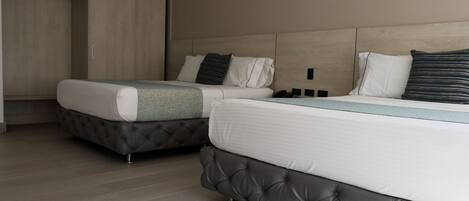 A hotel room with two beds, a wardrobe, and a built-in air conditioning unit.