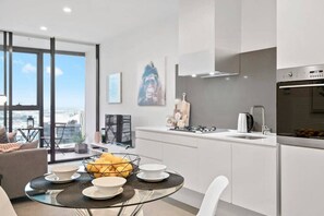 A modern kitchen with a large window, a dining area with a glass table, and a view of the city.