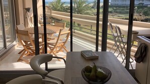 Een balkon met een houten tafel, stoelen en een schaal fruit.