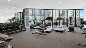 A modern gym with various exercise equipment, large windows, and a city view. - Dexter - Resort Living Gym, Sauna, Pool, Wi-Fi (Southbank)