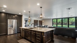Una cocina moderna con una isla grande, electrodomésticos de acero inoxidable e iluminación colgante.