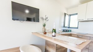 A modern kitchen with a wooden countertop, a built-in TV, a vase with lavender, and a bottle of champagne. - Mobile Home Plumeria 2 (Biograd)