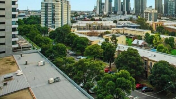 A cityscape with high-rise buildings, a parking area, and green spaces.