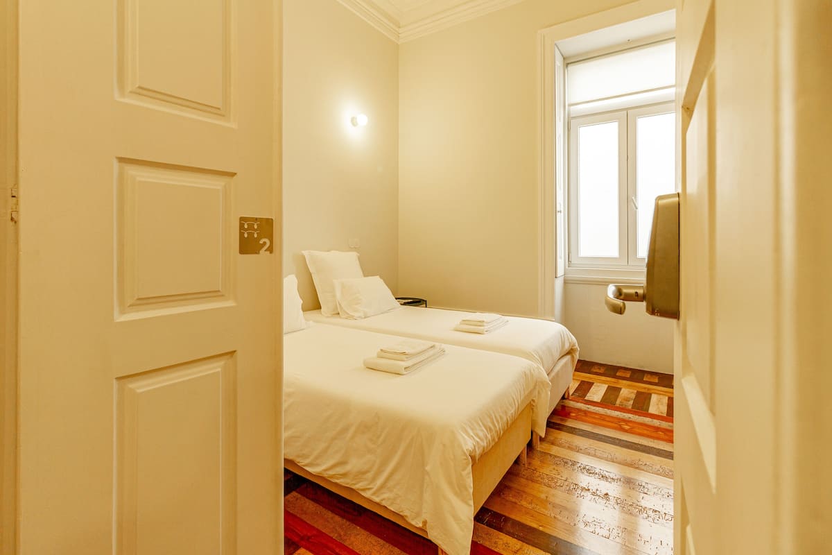 Un dormitorio con dos camas, una ventana y una puerta.