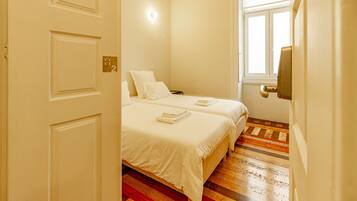 A bedroom with two beds, a window, and a door.
