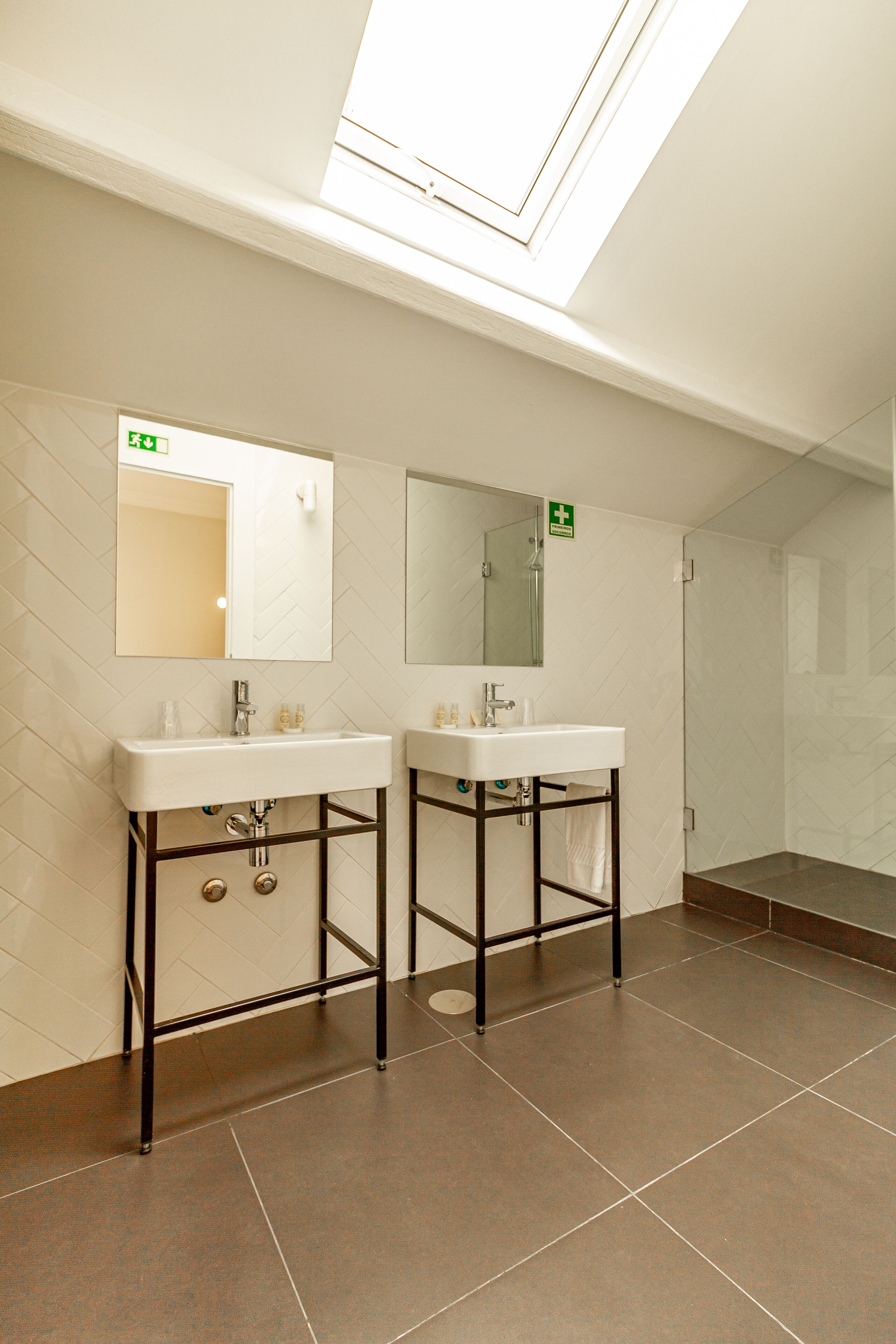 Une salle de bain moderne avec deux lavabos, un grand miroir et une lucarne.