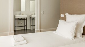 Habitación de hotel con una cama grande, dos almohadas, cabecero, baño con espejo y lavabo.